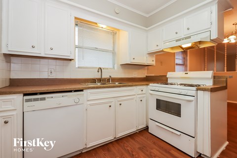 A kitchen with white cabinets and appliances.