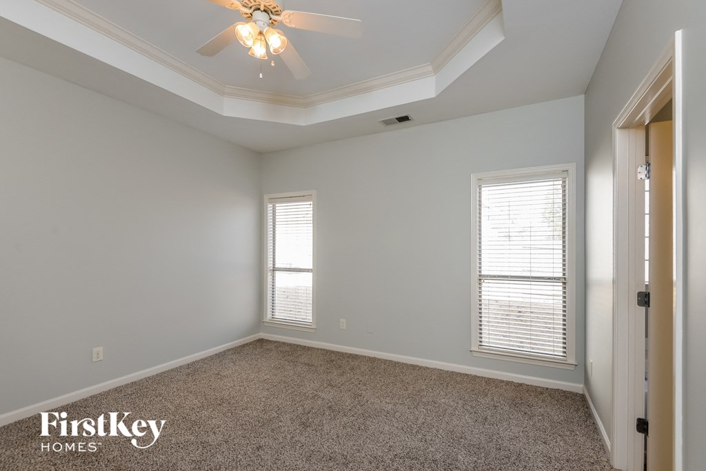 a bedroom with a ceiling fan and two windows