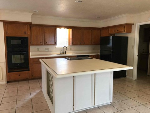 A kitchen with a black refrigerator and white countertops.
