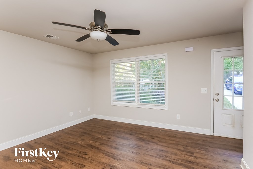 A room with a ceiling fan and wooden flooring.