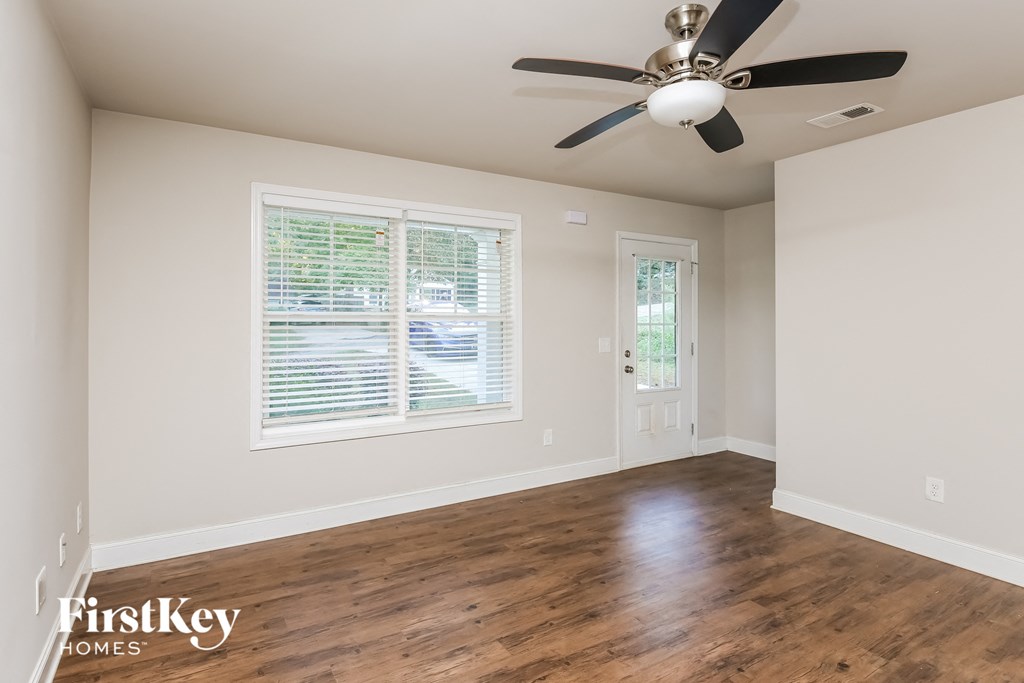 A room with a ceiling fan and wooden flooring.