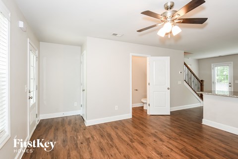 A spacious room with a ceiling fan and wooden flooring.