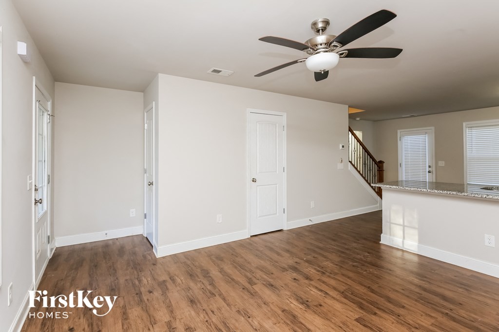 A spacious room with a ceiling fan and wooden flooring.