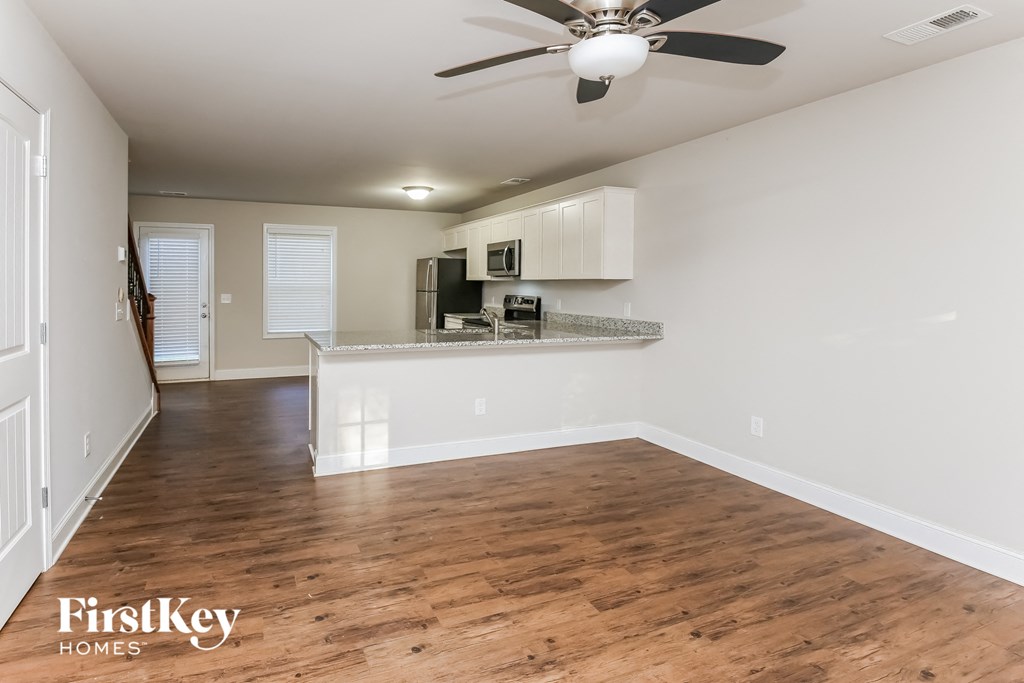 A spacious room with wooden floors and a ceiling fan.