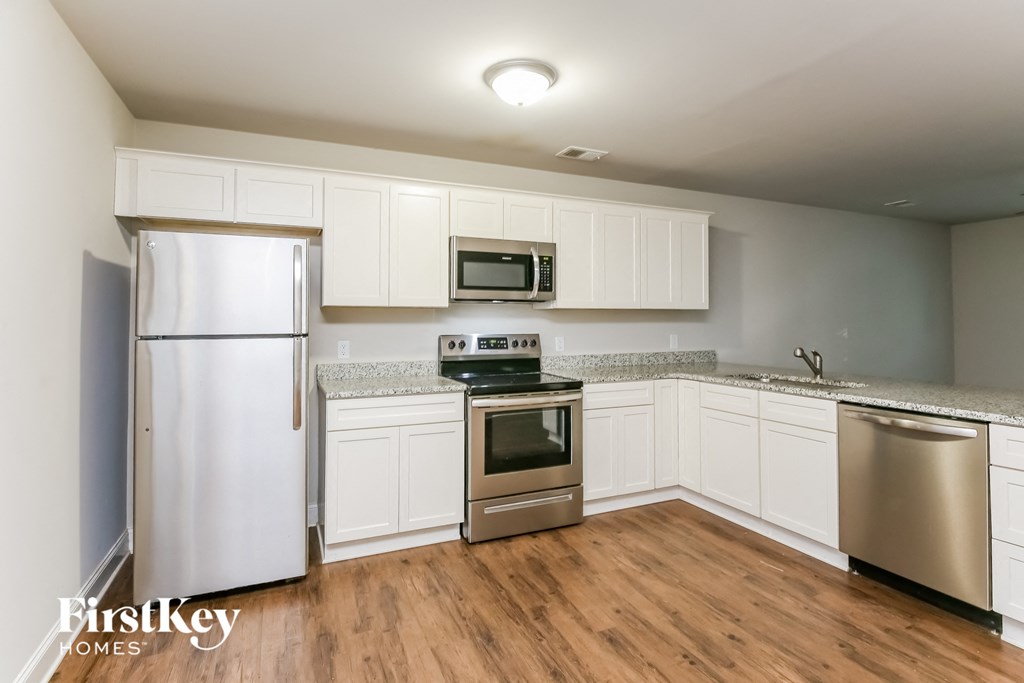 A kitchen with a refrigerator, oven, microwave, and dishwasher.