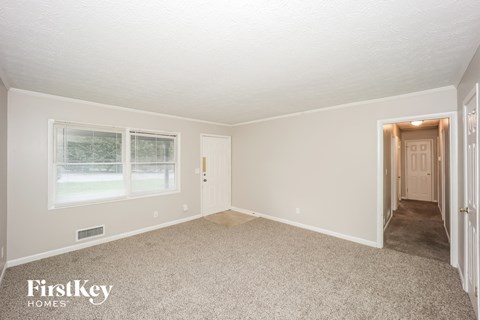 A room with a carpet floor and a doorway leading to another room.