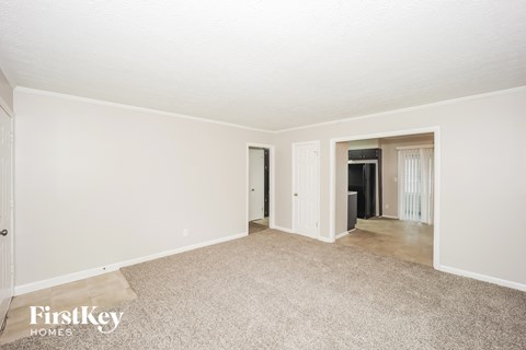 A carpeted room with a door and a window.