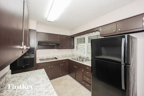 A kitchen with a black refrigerator and stove top oven.