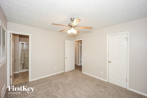 A spacious room with a ceiling fan and carpeted floor.