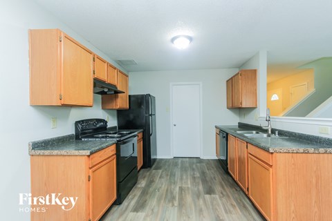 A kitchen with wooden cabinets and a black refrigerator.