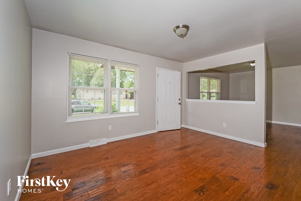 A room with wooden floors and a window with blinds.