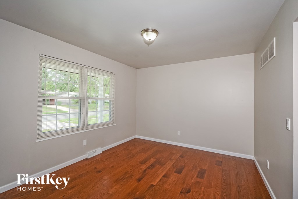 A room with wooden floors and a window with blinds.