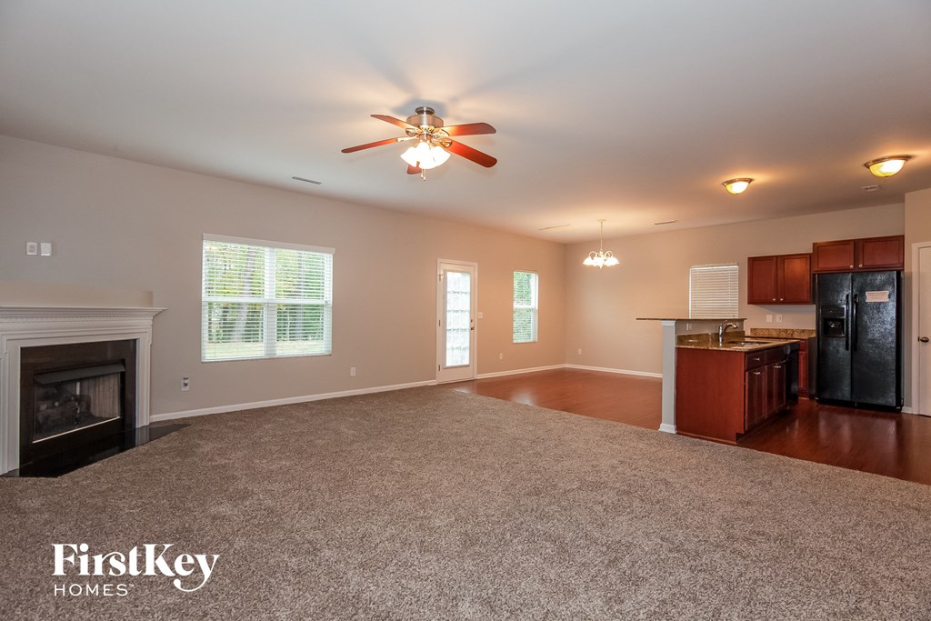 an empty living room with a fireplace and a ceiling fan