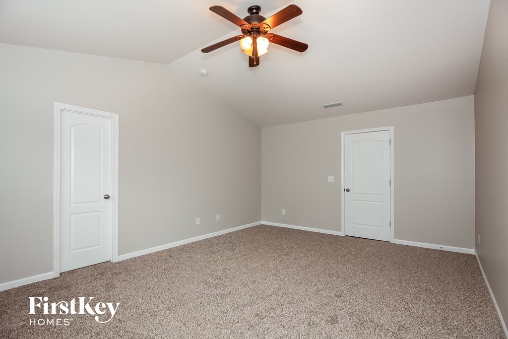 the master bedroom has a carpeted floor and a ceiling fan