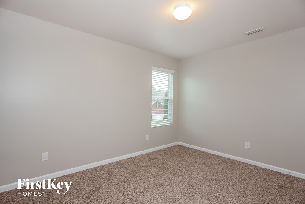 a bedroom with white walls and carpet and a window