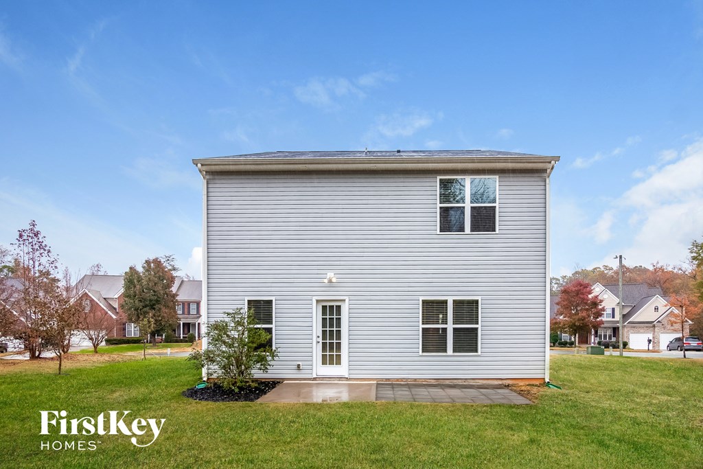 a single story home with white siding on a green lawn