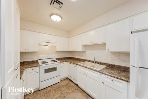 A kitchen with white cabinets and appliances.