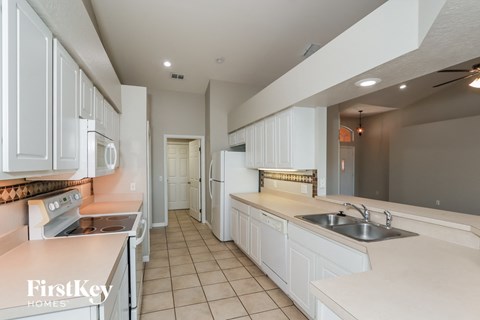 a large kitchen with white cabinets and counters and a sink