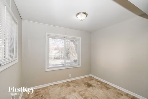 the living room of a home with a large window and wooden floors