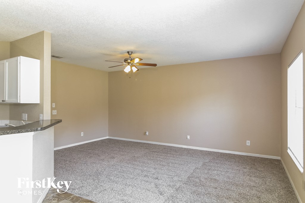 A spacious room with a ceiling fan and a counter with cabinets.