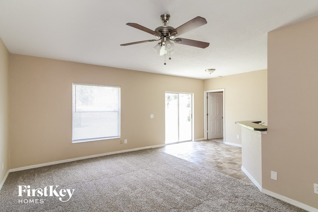 A spacious room with a ceiling fan and carpeted floor.