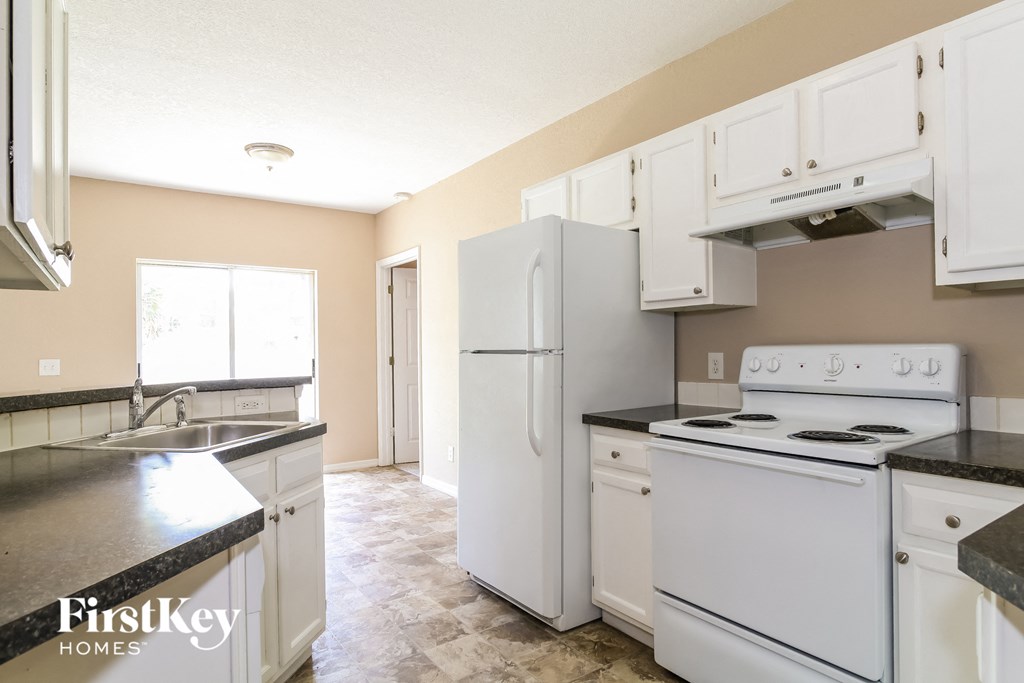 A kitchen with white appliances and a black counter top.
