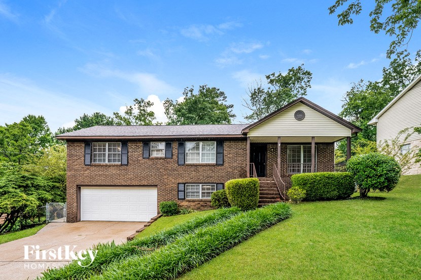 A brick house with a white garage door and a well-kept lawn.
