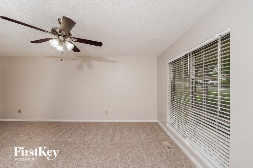 A room with a ceiling fan and a window with blinds.