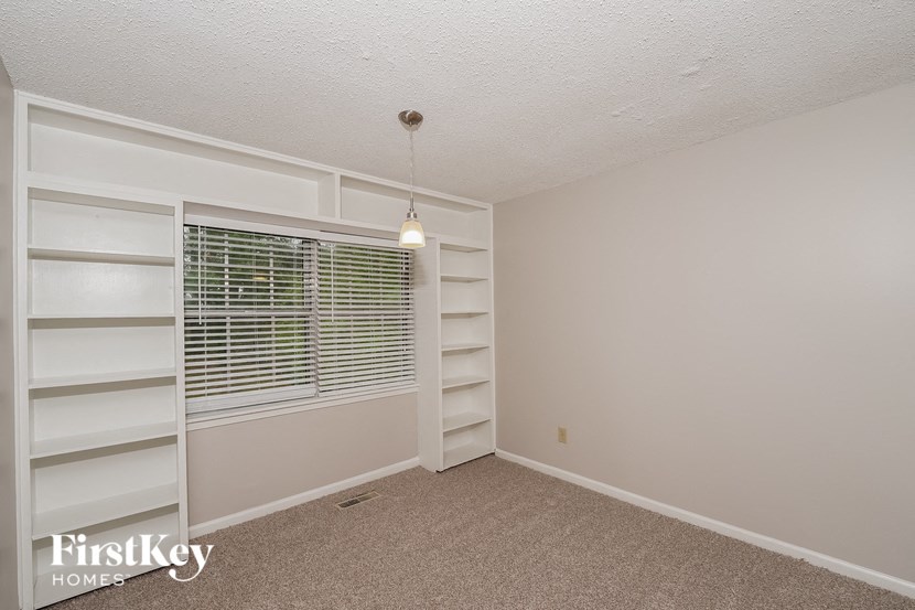 A room with a window covered by blinds and a hanging light fixture.
