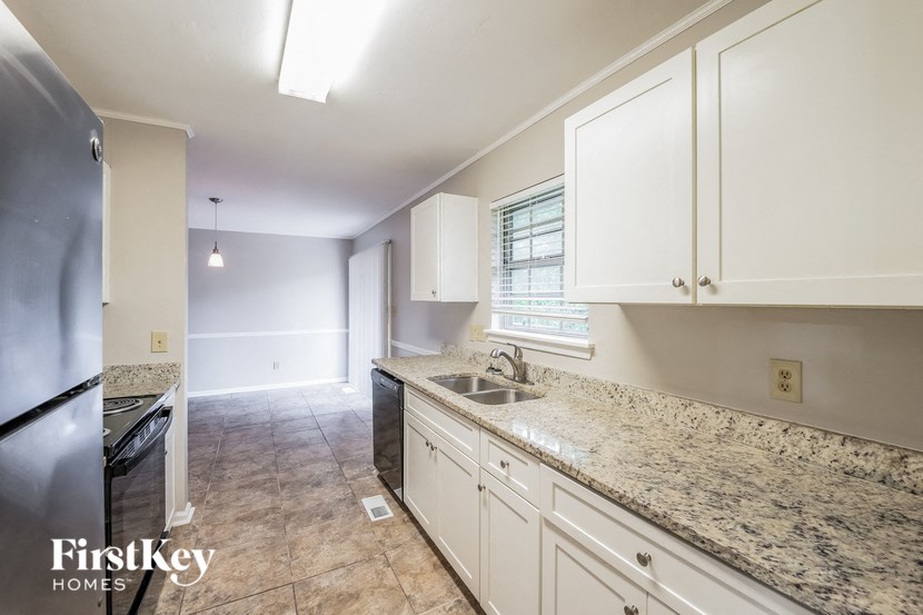 A kitchen with granite countertops and white cabinets.