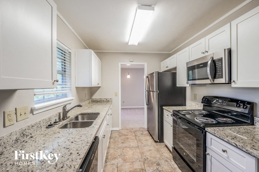 A kitchen with granite countertops and white cabinets.