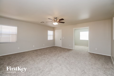 the spacious living room with ceiling fan and carpeting
