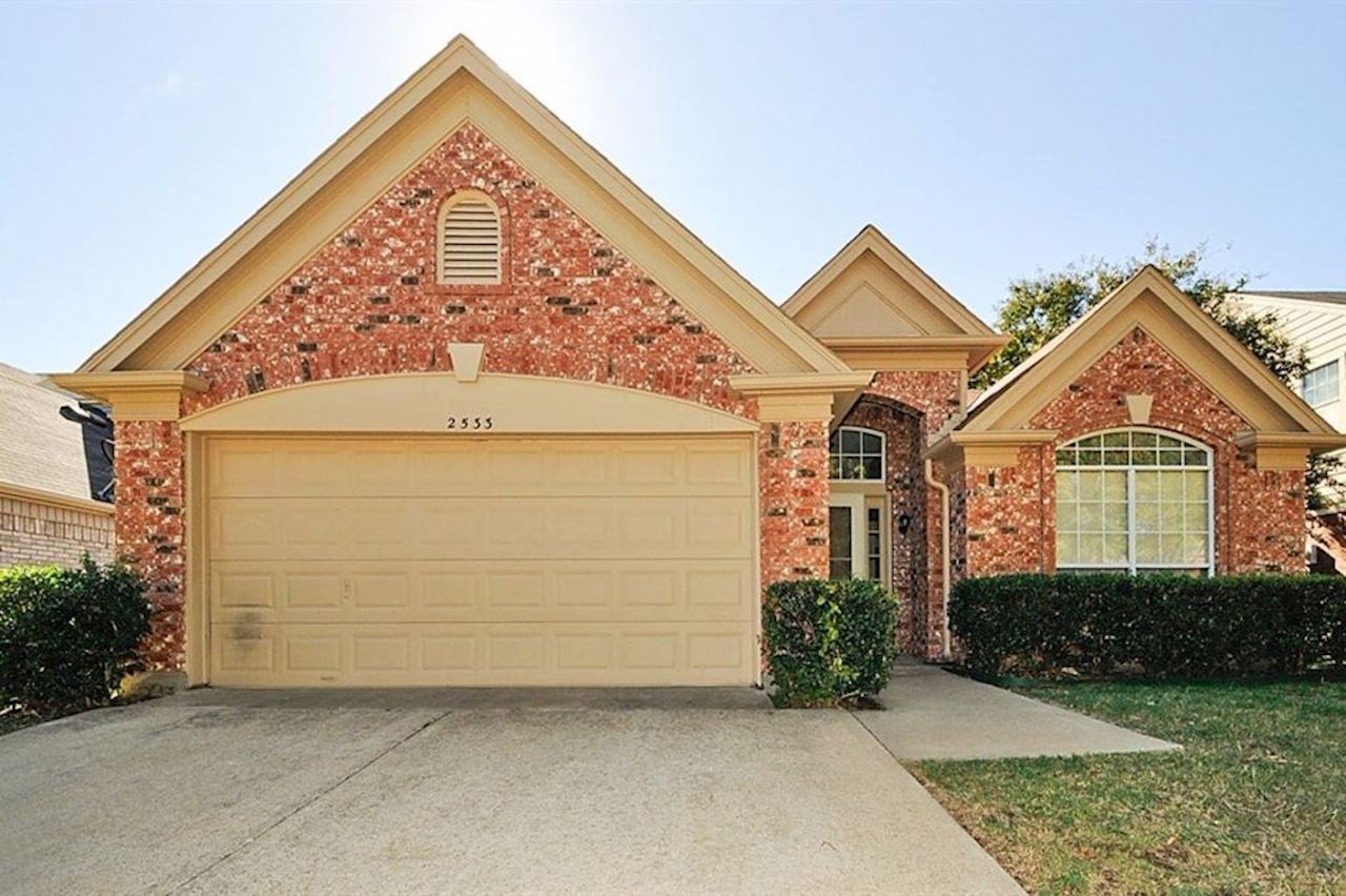 the front of a brick house with a white garage door