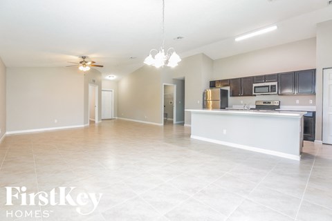 A spacious kitchen and living room with a tiled floor and a ceiling fan.