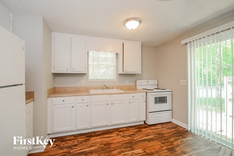 A kitchen with white cabinets and a wooden floor.