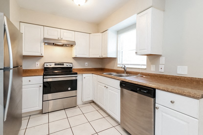 A kitchen with white cabinets and a stainless steel refrigerator.