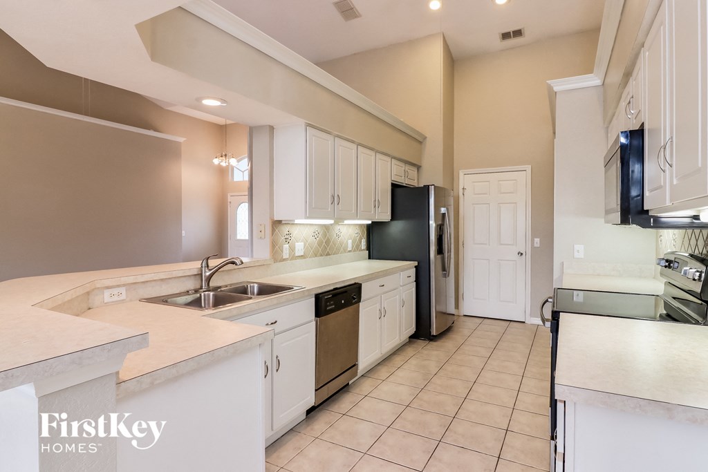 a kitchen with white cabinets and a black refrigerator