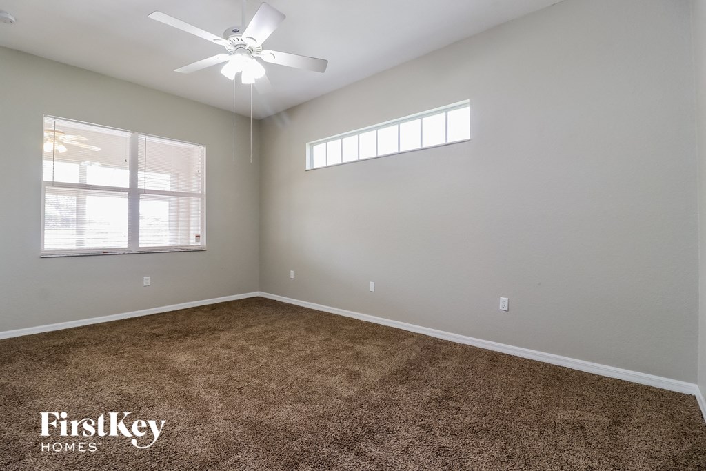 the master bedroom has carpeted floors and a ceiling fan