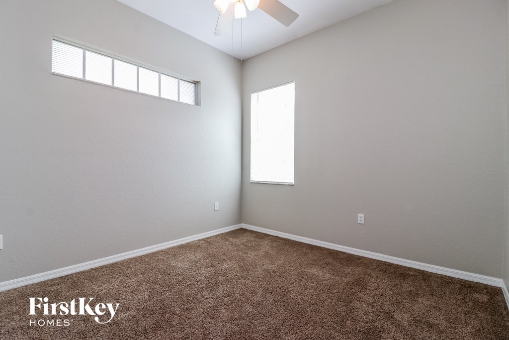 a carpeted room with a window and a ceiling fan