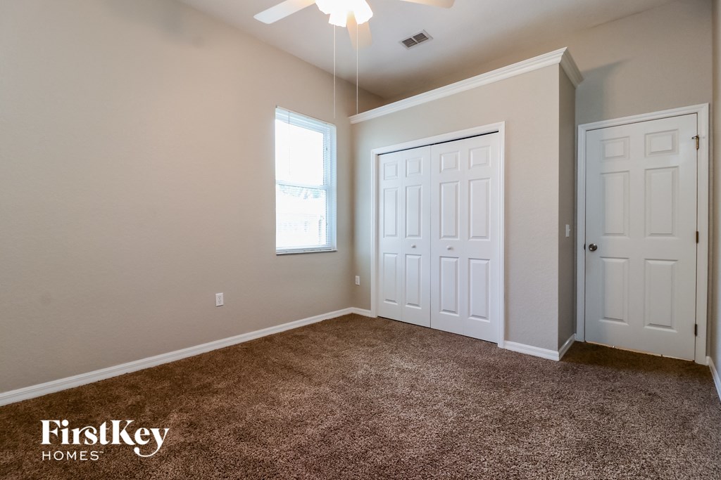 the master bedroom with carpeted flooring and two closets