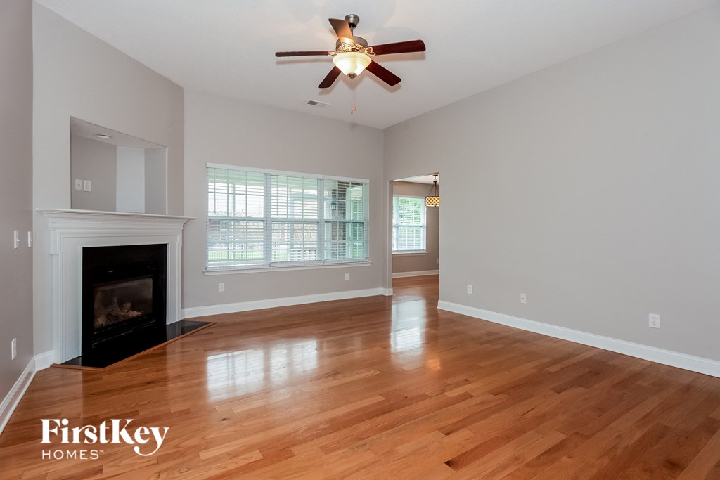 A spacious room with a fireplace and a ceiling fan.