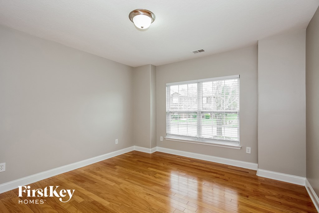 A room with wooden floors and a window with blinds.