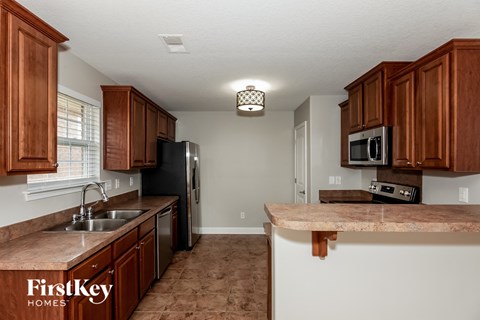 A kitchen with brown cabinets and a marble countertop.