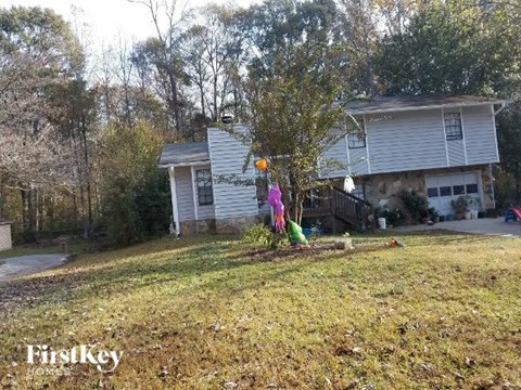 A house with a yard and a tree with a windmill on top.