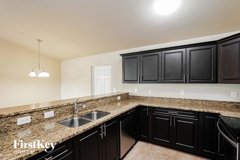 A kitchen with black cabinets and a granite countertop.