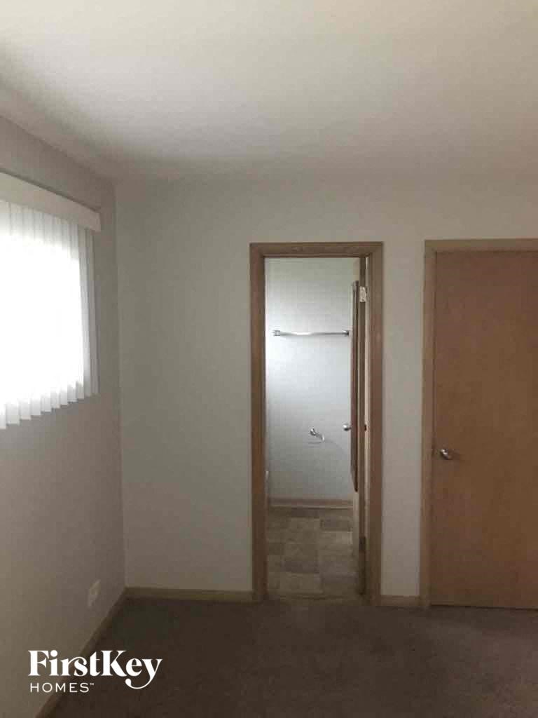 an empty room with a door to a hallway and a closet