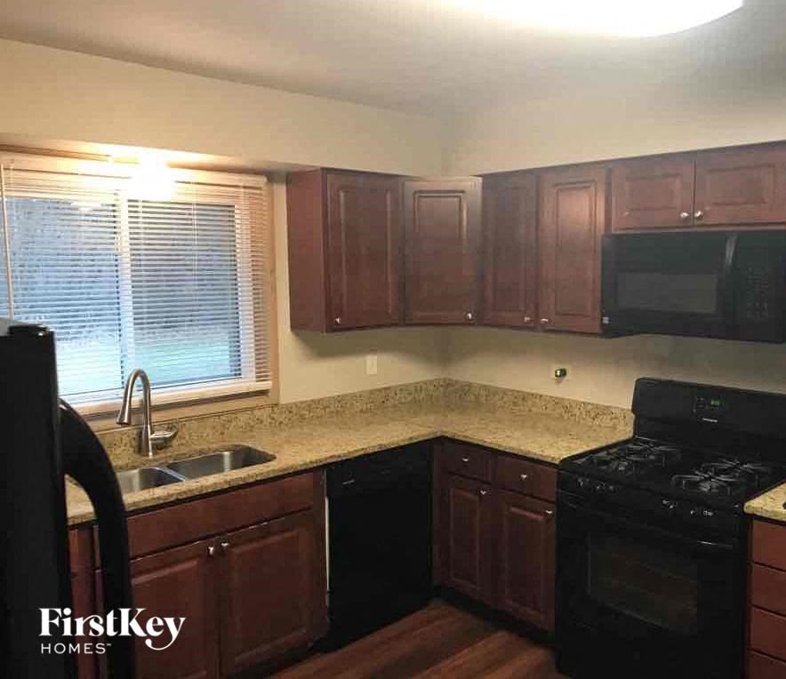 a kitchen with wooden cabinets and a black stove and a sink