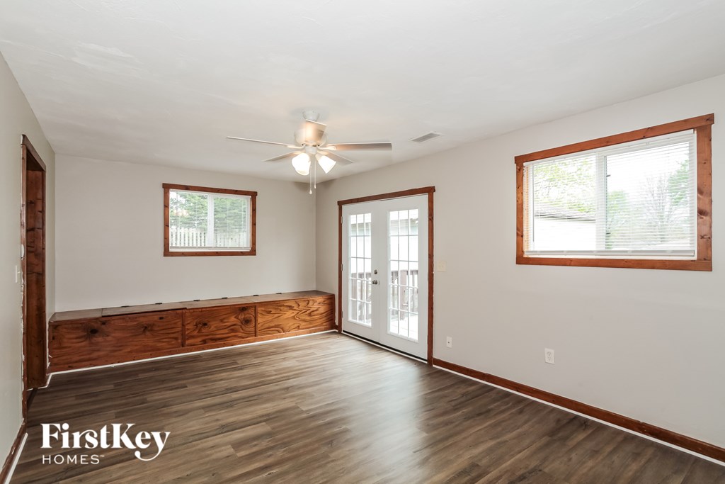 A spacious room with wood flooring and a ceiling fan.