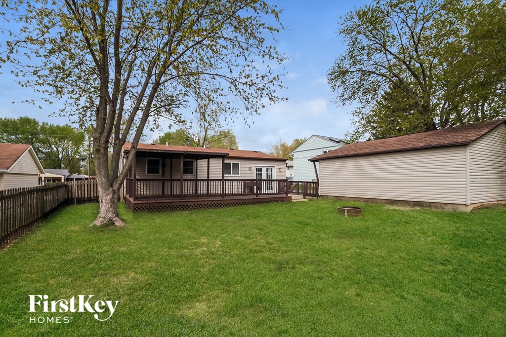 A tree stands in a grassy yard in front of a house.