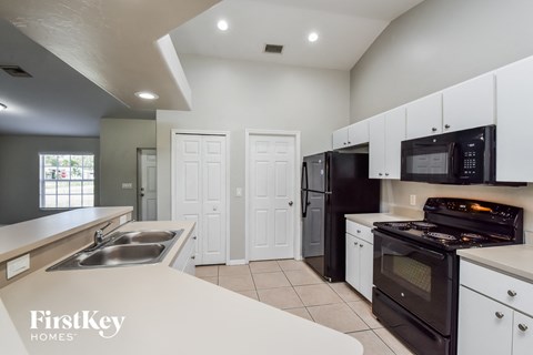 a kitchen with white counters and black appliances and a sink